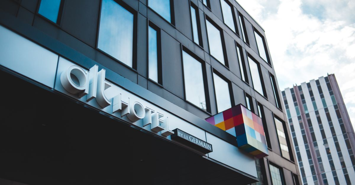 Contemporary hotel façade with glass windows and distinctive colorful signage.