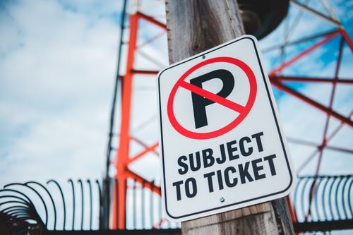 Free Close-up of a no parking sign with a tower in the background, emphasizing traffic restrictions and warnings. Stock Photo