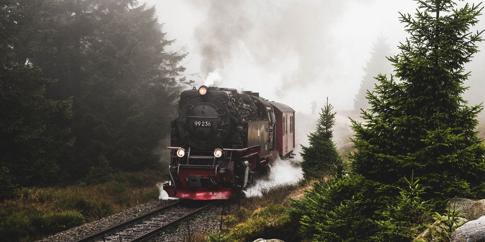 A classic steam locomotive traveling through a misty forest