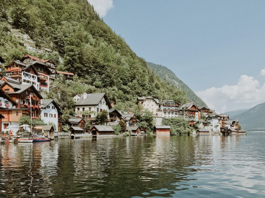 Charming houses nestled by an Alpine lake with mountain scenery.