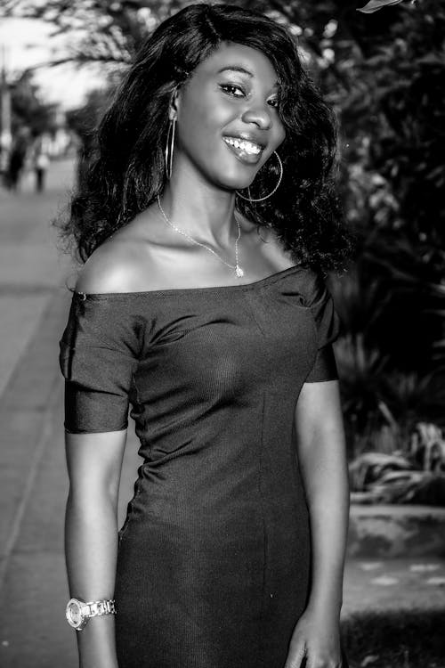 Black and white of happy African American female with bare shoulders smiling and looking at camera