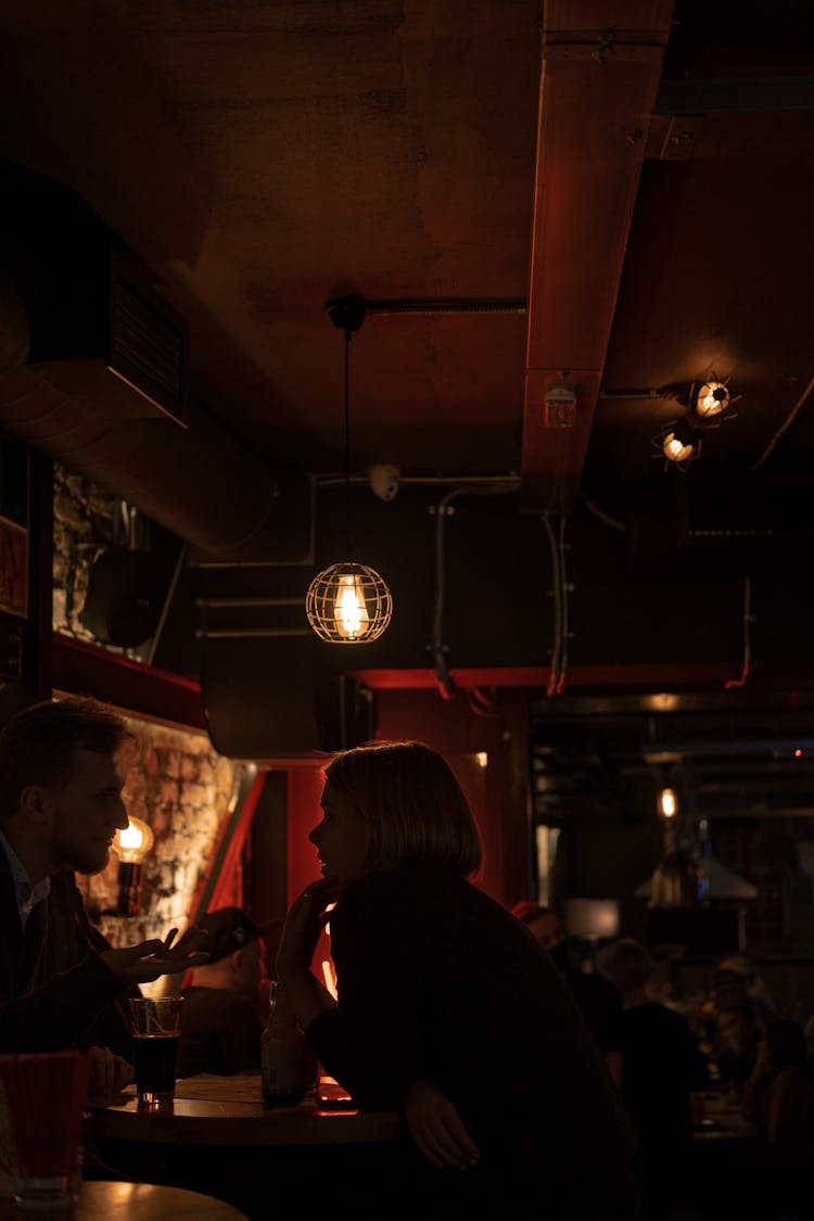 Couple Talking And Sitting At Table In Pub