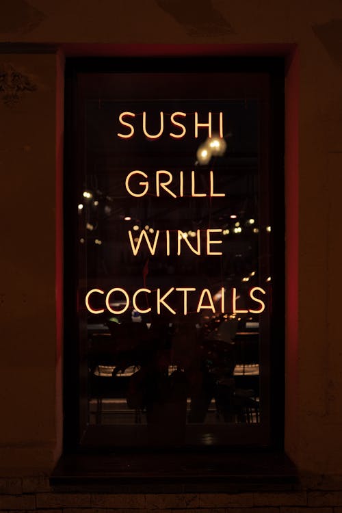 Bright neon signboard with sushi grill wine and cocktails