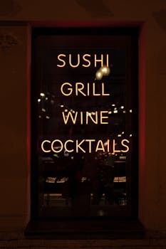A glowing neon sign showcasing sushi, grill, wine, and cocktails at night.