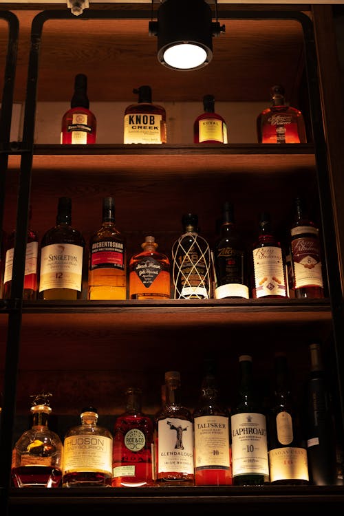 From below of interior of restaurant with bottles of different alcohol placed on shelves under bright illumination