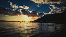 海滩风景优美，日落壮丽，背景是船只和山脉的轮廓