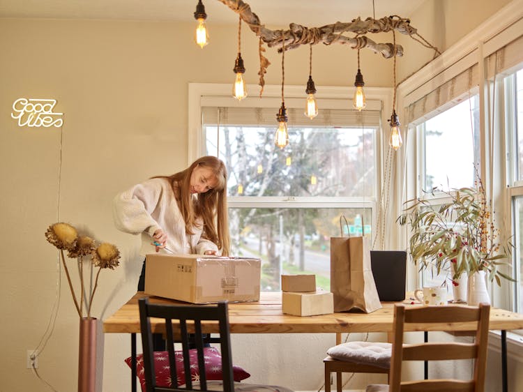 Woman Unpacking Boxes With Orders At Home