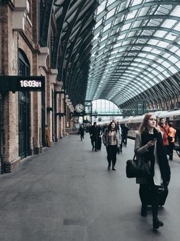 People walking in King's Cross Station under the architectural roof, showcasing busy city life.