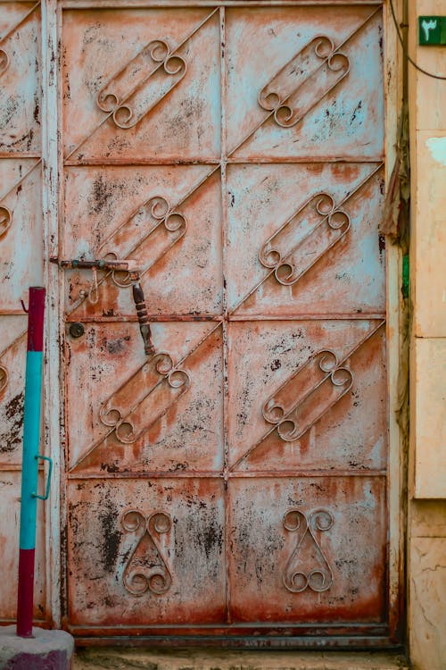 An Old Steel Door Near a red and Blue Steel Pole