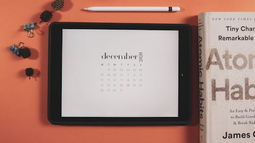 Close-Up Shot of an Ipad beside a Book