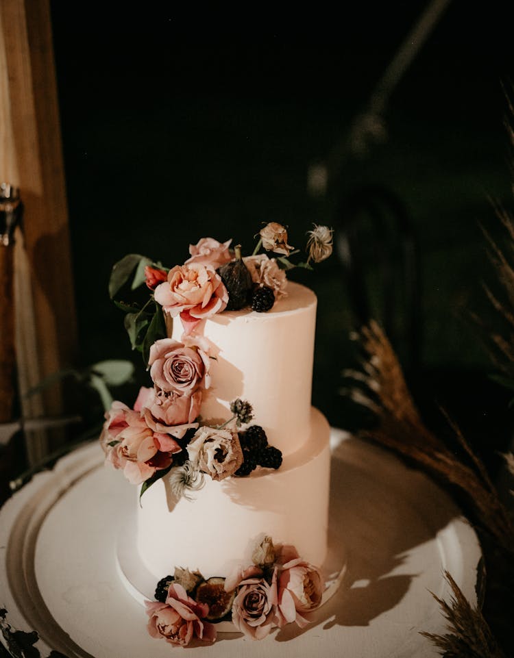 A White Wedding Cake Decorated With Flowers And Leaves