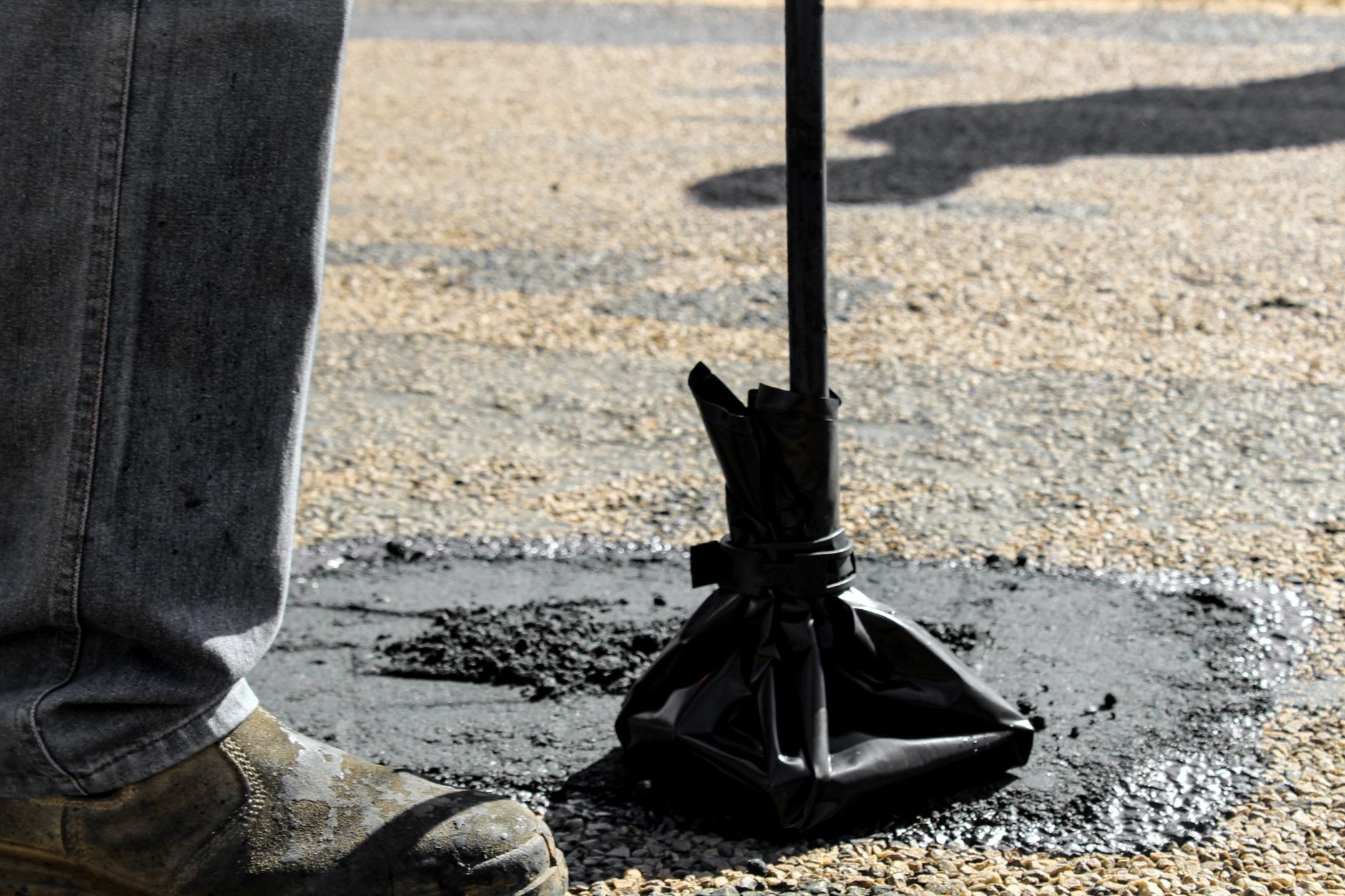 Homeowner applying asphalt sealer with a squeegee on a residential driveway