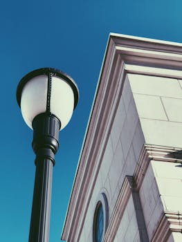 低角度拍摄的现代建筑立面与灯柱，在蔚蓝天空下展现城市风貌