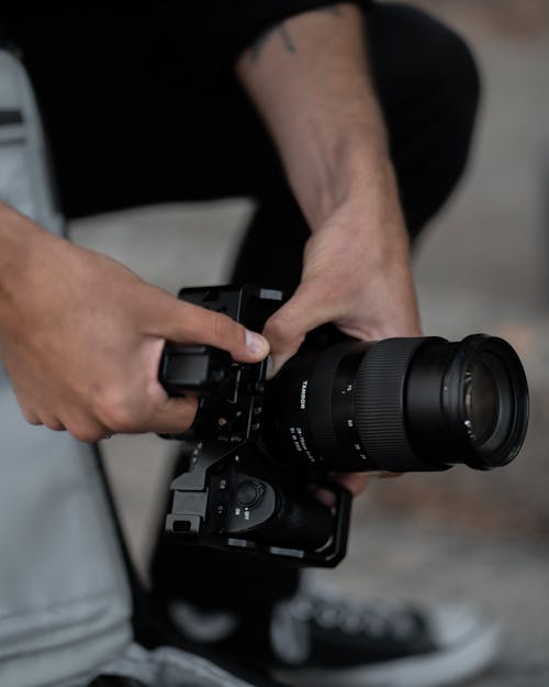 Close-Up Shot of a Person Holding a Black DSLR Camera