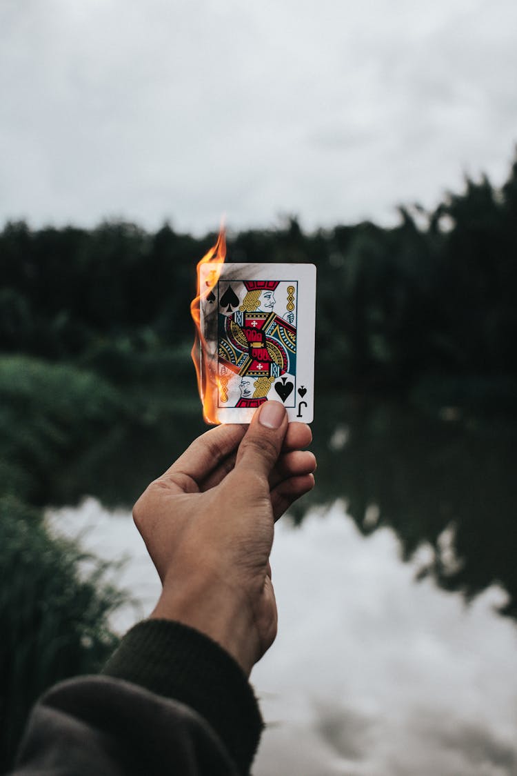 Close-Up Shot Of A Person Holding A Burning Poker Card