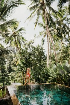 A woman enjoys a tropical oasis in Bali, surrounded by lush palm trees.