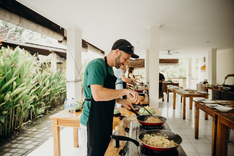 A Man Wearing Black Apron Cooking Food In A Cooking Competition