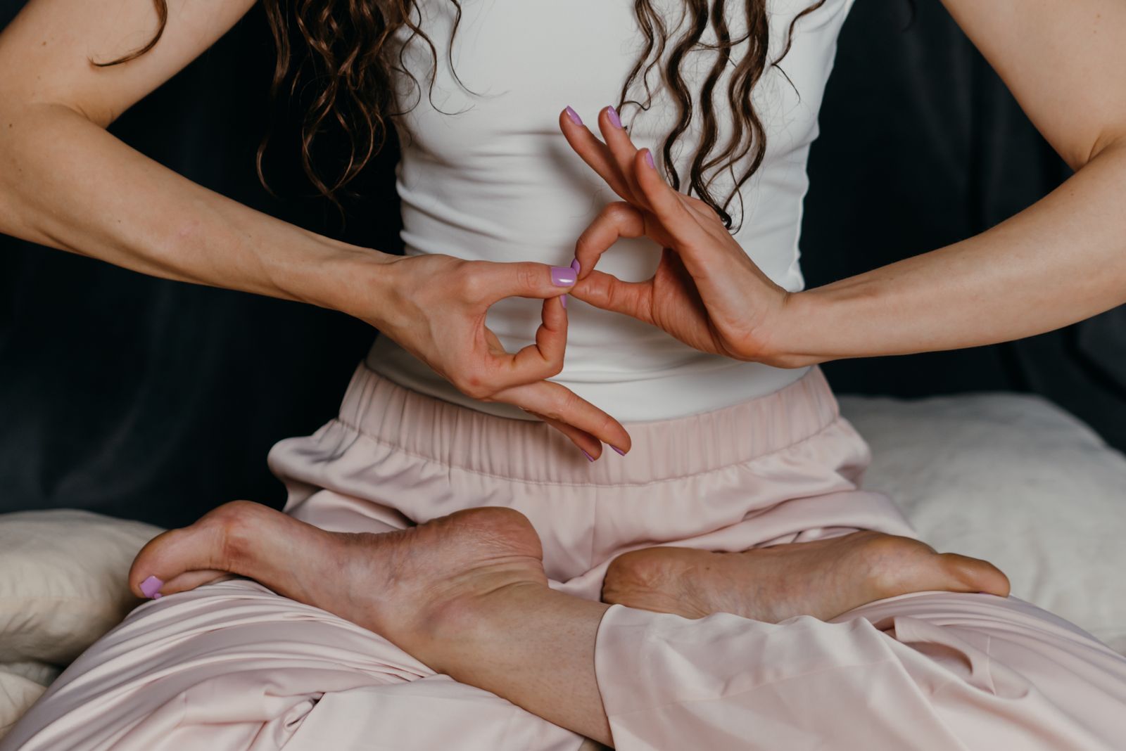 Close-up of hands forming a yoga mudra gesture during seated cross-legged meditation