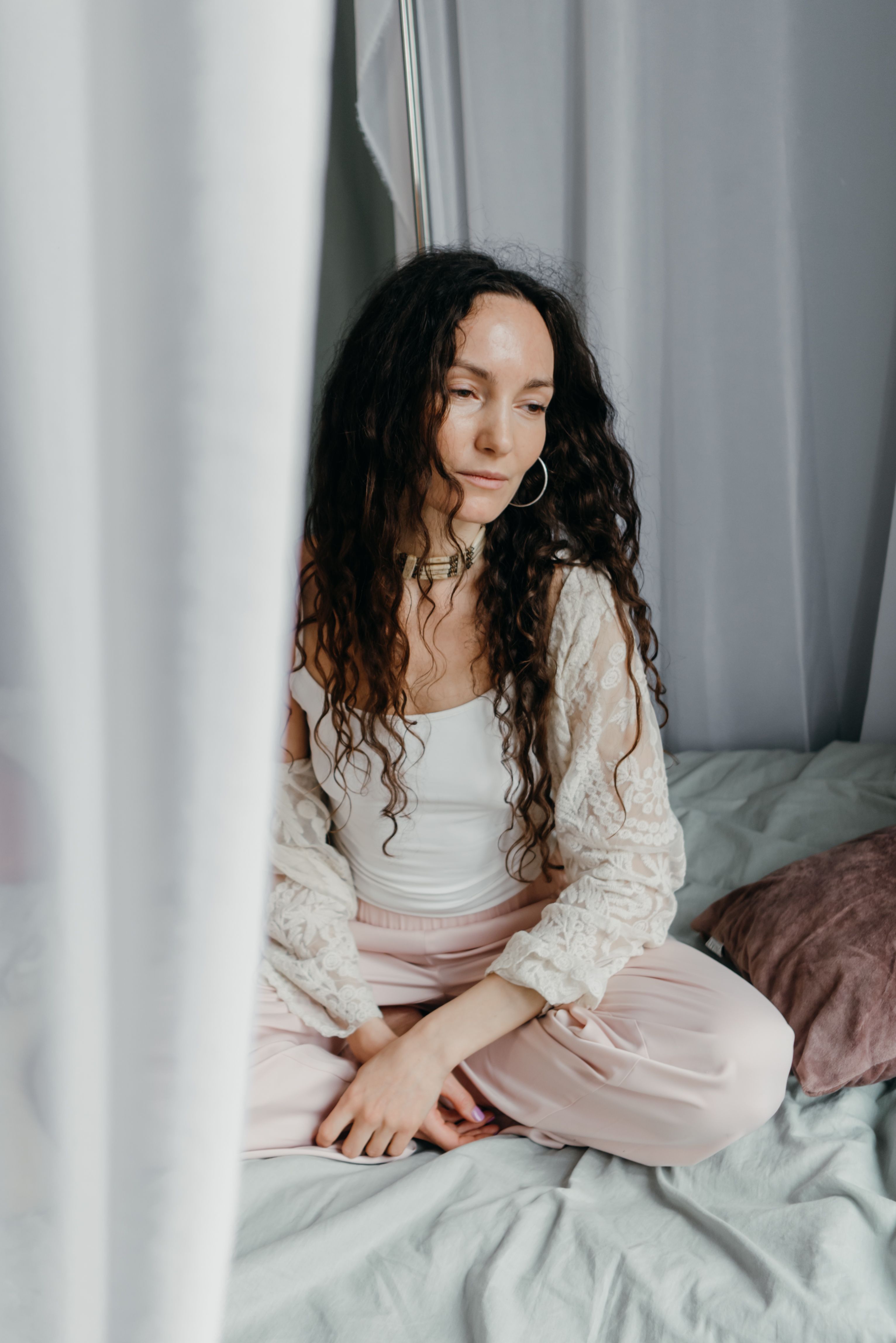 Serene woman practicing meditation on a bed, creating a calm and tranquil atmosphere.
