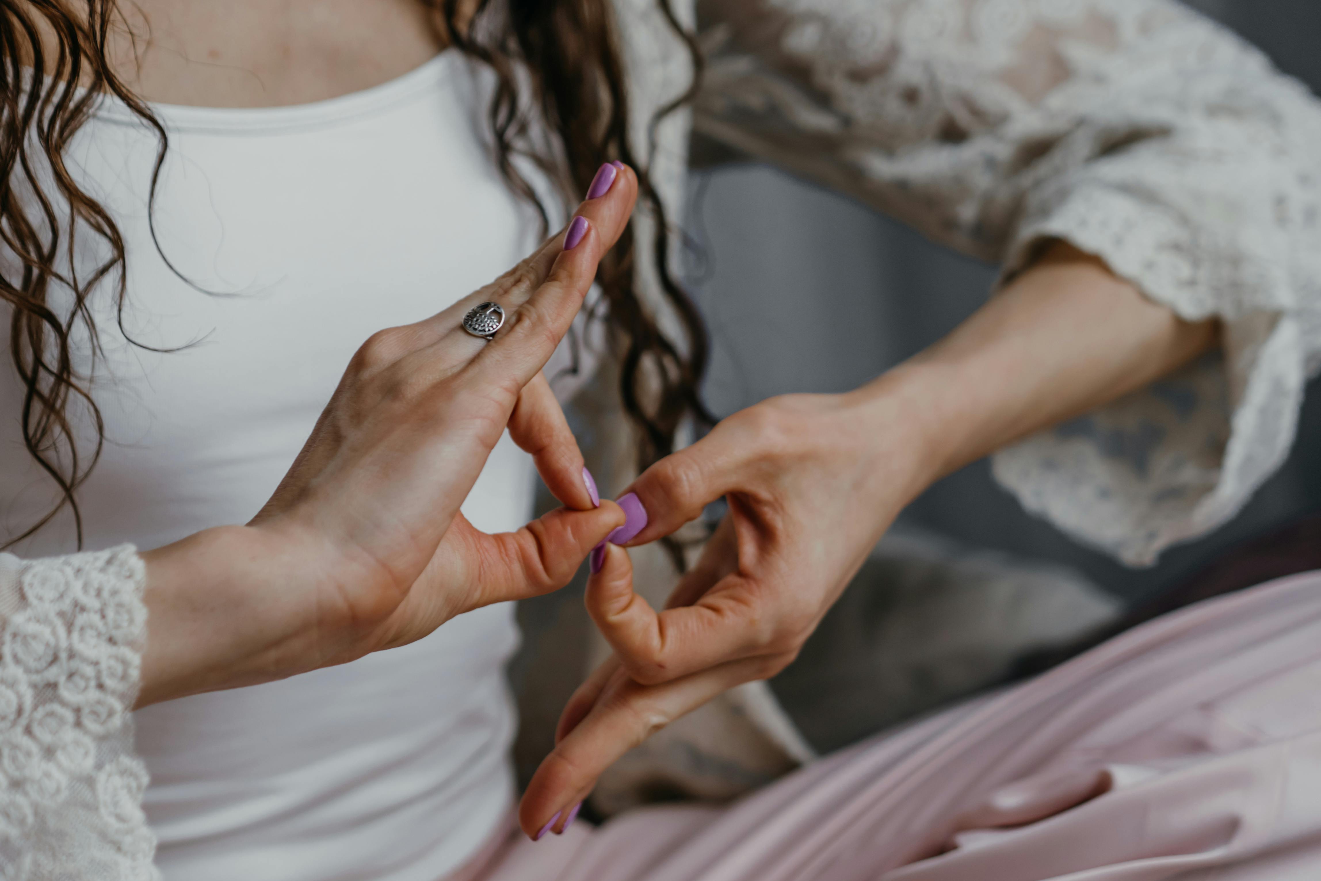 Close-up of a woman practicing yoga hand mudras indoors promoting relaxation and mindfulness.