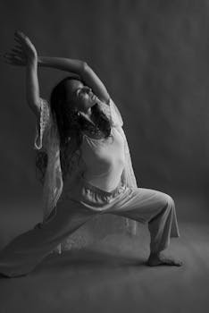Monochrome image of a woman performing a graceful yoga pose, showcasing flexibility and mindfulness.