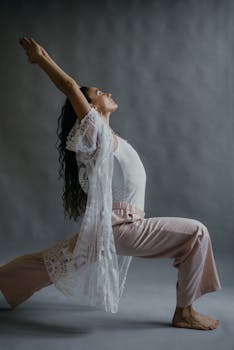 A woman performing a yoga pose on a gray background, embodying peace and flexibility.