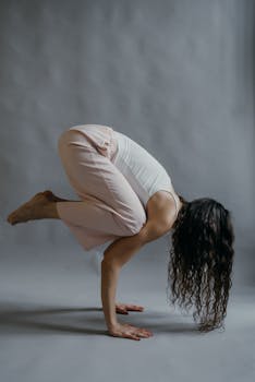 A woman in a balancing yoga pose indoors, exemplifying strength and mindfulness.