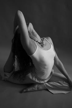 Artistic black and white photo of a woman in a yoga pose, focusing on flexibility and wellness.