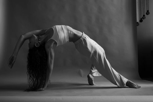 Free A woman in a graceful yoga pose in a monochrome studio setting, embodying fitness and flexibility. Stock Photo