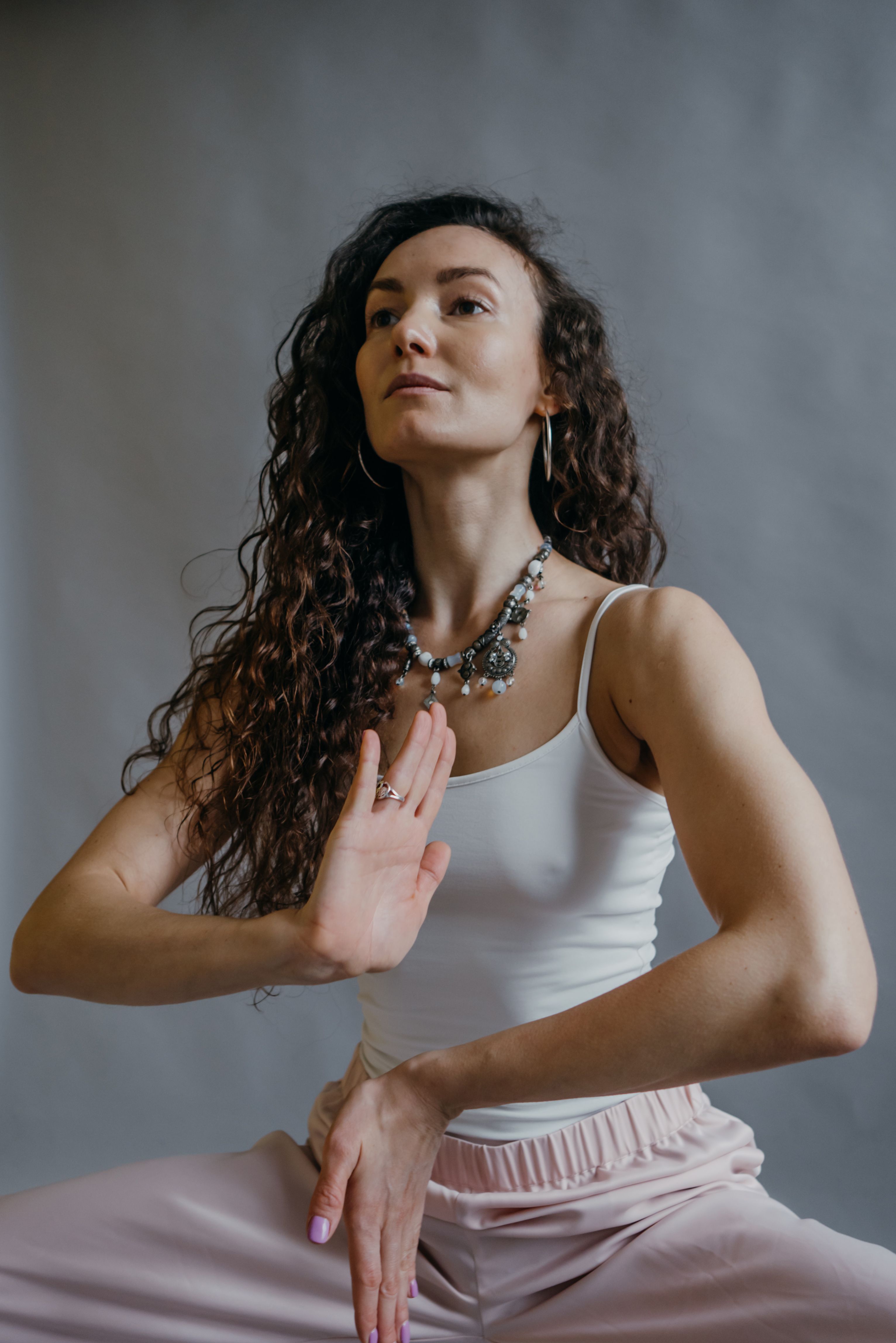 Woman with curly hair practicing yoga in a serene indoor setting, exuding mindfulness and relaxation.