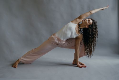 Free A woman demonstrates a yoga pose in a studio setting, focusing on flexibility and wellness. Stock Photo
