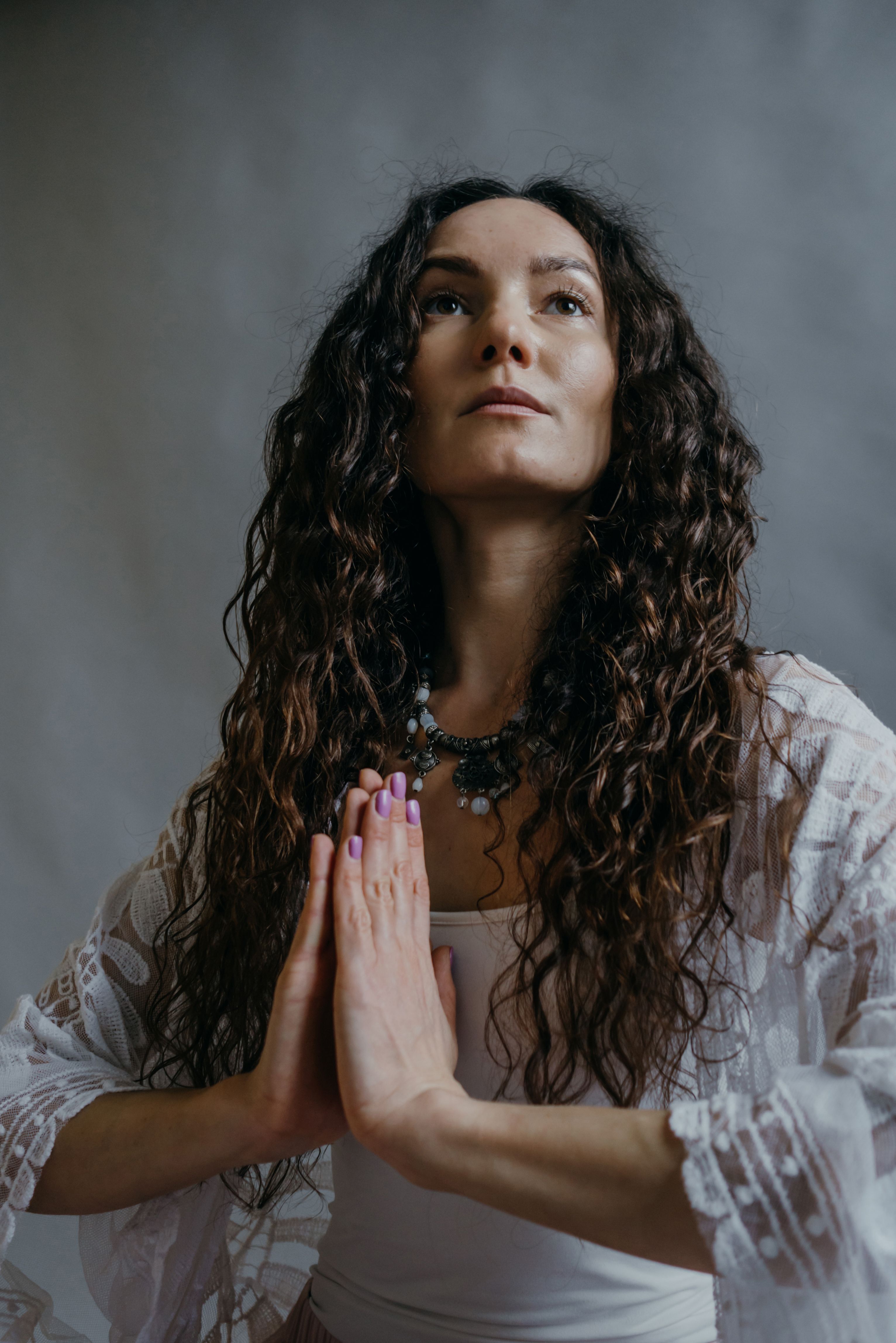A serene woman engaged in a meditation pose with hands together, symbolizing mindfulness and tranquility.