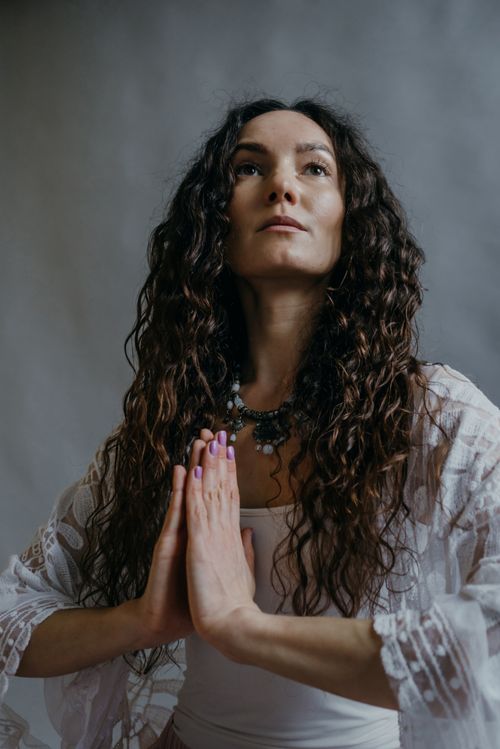 Free A serene woman engaged in a meditation pose with hands together, symbolizing mindfulness and tranquility. Stock Photo