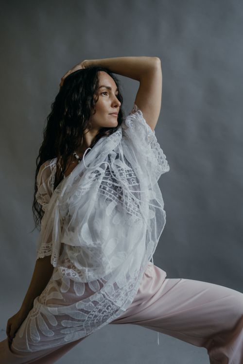 Free Sophisticated portrait of a woman in stylish white lace top posing gracefully indoors. Stock Photo