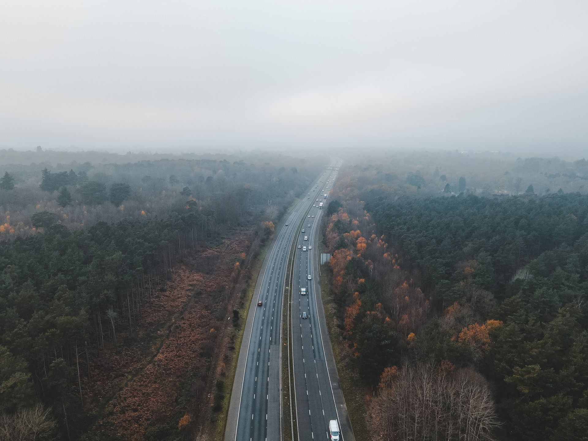 Tráfico circulando por una autopista brumosa de varios carriles, que ilustra las emisiones de los vehículos y la contaminación del aire.