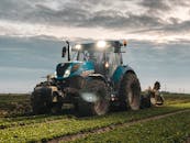 Agricultural tractor plowing green field