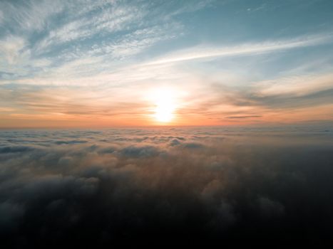 Breathtaking view of endless orange and blue sky with white foggy clouds with sun in sunset