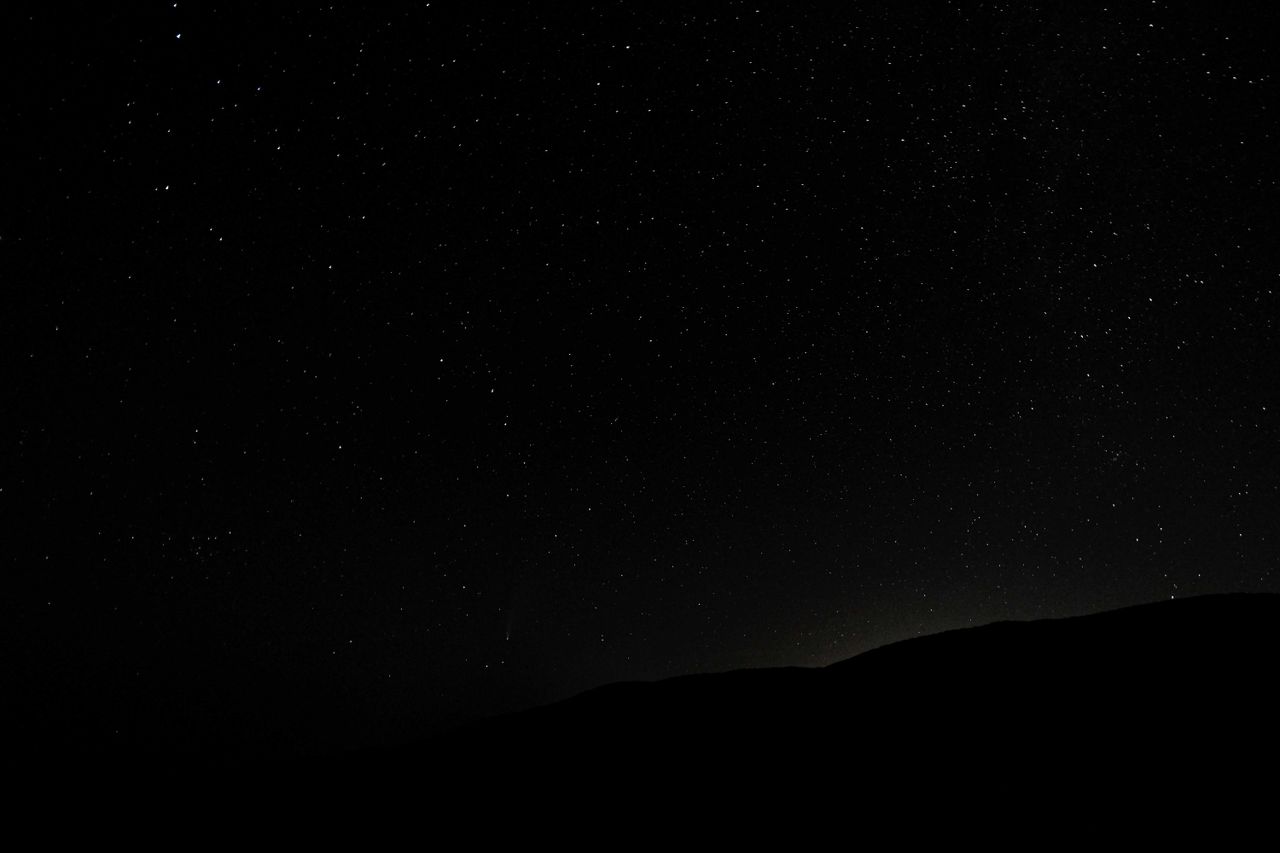 dark endless sky covered with shining luminous stars above silhouette