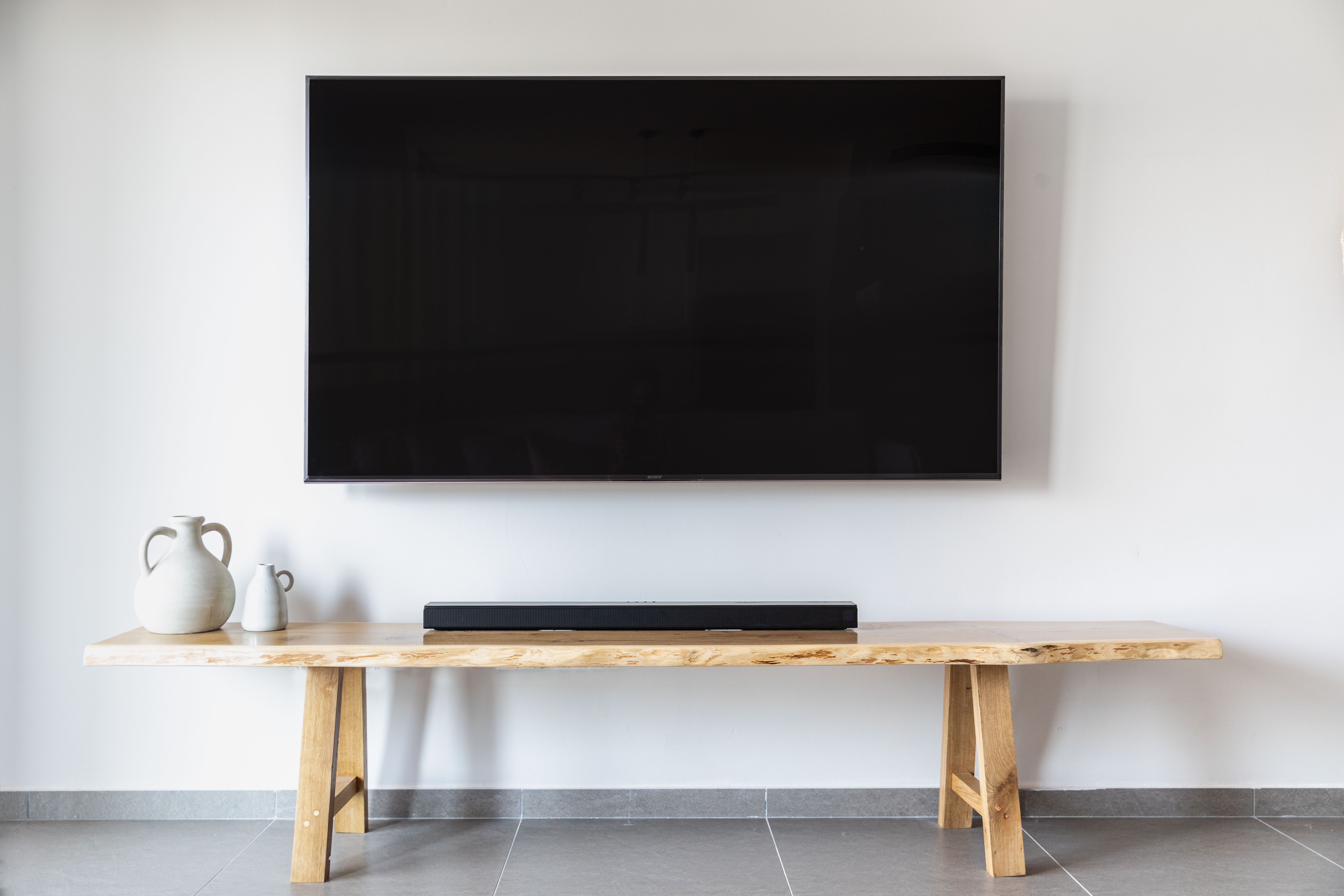 Flat screen TV mounted above a wooden console in a styled living room