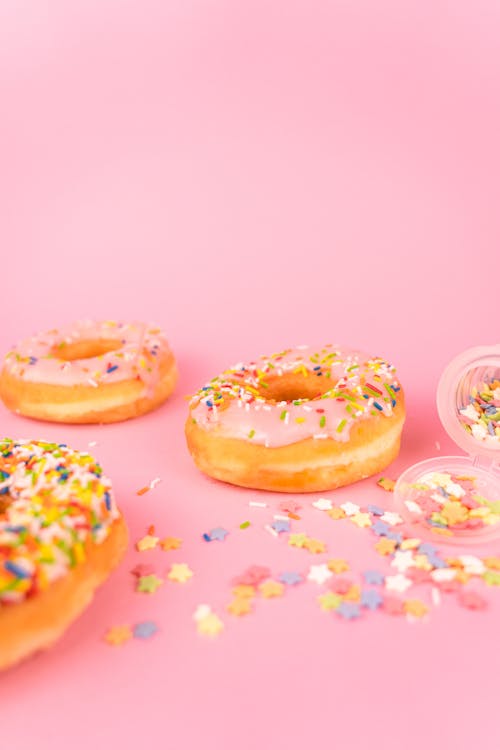 Delicious Doughnuts with Sprinkles on Pink Surface