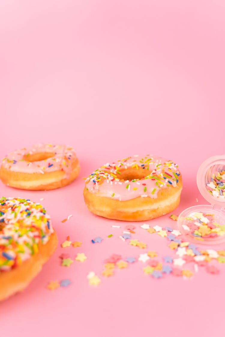 Delicious Doughnuts With Sprinkles On Pink Surface