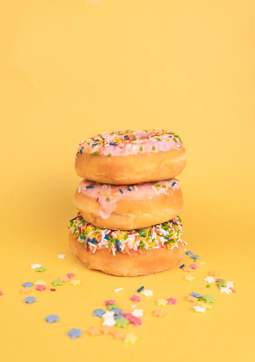 A Stack of Delicious Doughnuts with Sprinkles on Yellow Surface