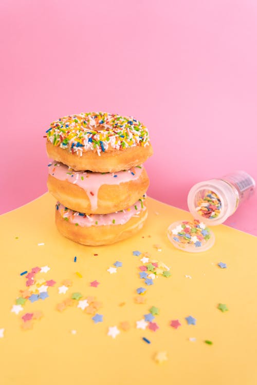 A Stack of Delicious Doughnuts with Sprinkles on Yellow Surface
