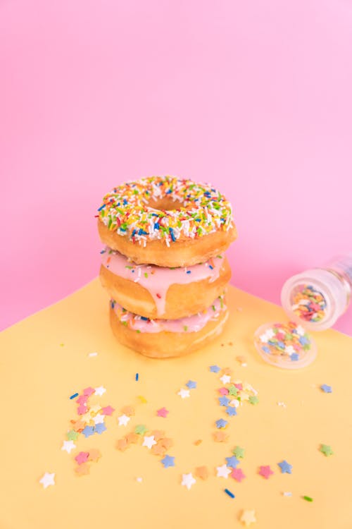 A Stack of Delicious Doughnuts with Sprinkles on Yellow Surface
