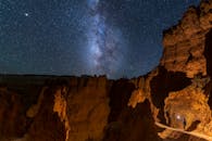 A Person Holding a Light at Bryce Canyon Under a Beautiful Starry Sky