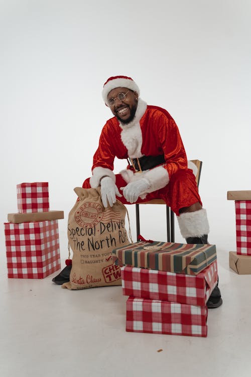 Free Man in Santa Costume Sitting near the Christmas Presents Stock Photo