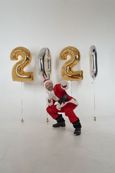 A joyful Santa Claus in a studio with 2021 balloons celebrating the New Year.