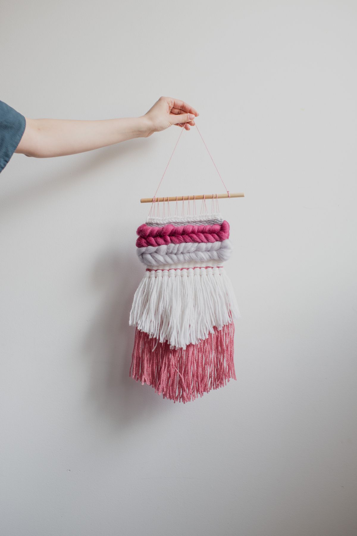 Yarn craft ideas with woven yarn wall art hanging from a wooden dowel