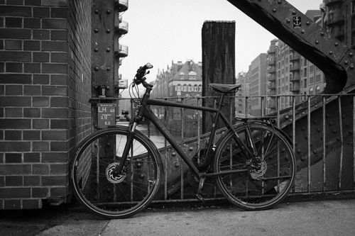Free A monochrome photograph capturing a bicycle parked against a brick wall with cityscape views. Stock Photo