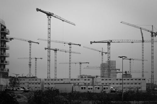 Grayscale Photo of Tower Cranes